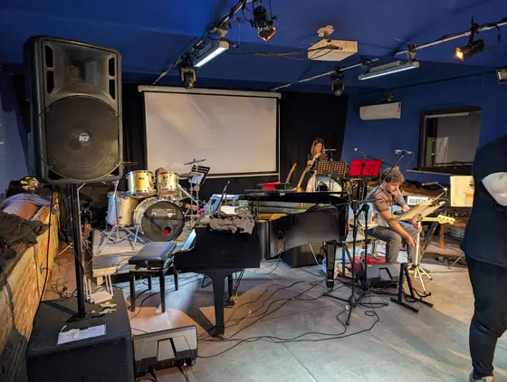 Allestimento del palco con pianoforte a coda, batteria e schermo
